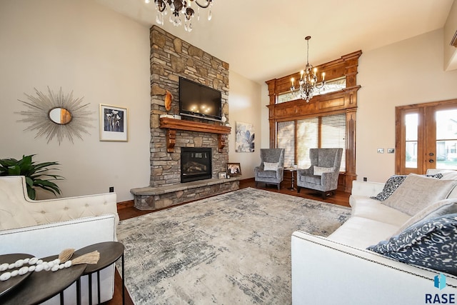 living room with a notable chandelier, dark hardwood / wood-style flooring, and a stone fireplace