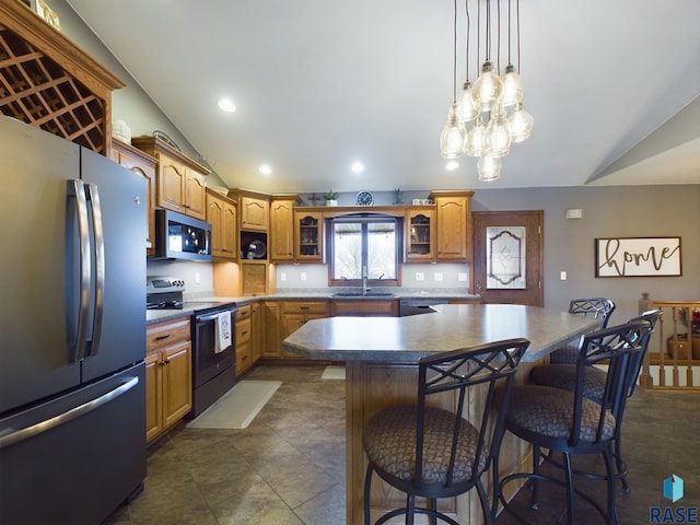 kitchen with a center island, sink, stainless steel appliances, vaulted ceiling, and a kitchen bar