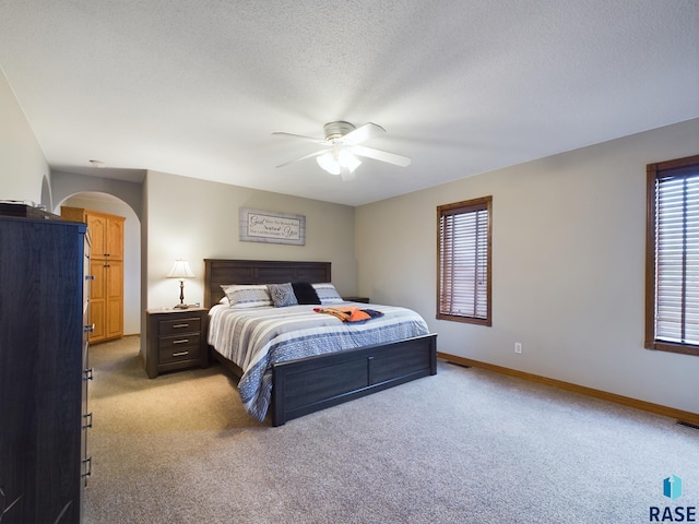 bedroom with ceiling fan, carpet, and a textured ceiling