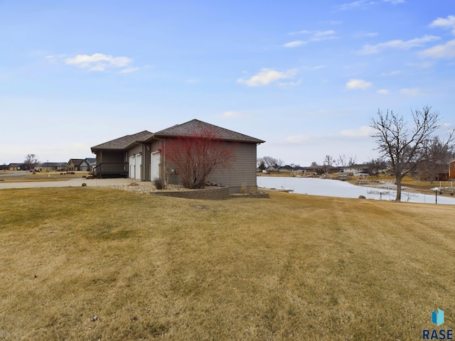 view of side of property with a yard, a water view, and a garage