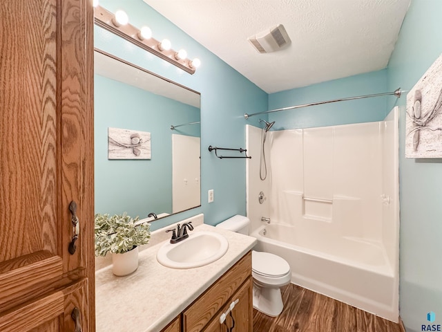 full bathroom with shower / bathtub combination, vanity, a textured ceiling, hardwood / wood-style flooring, and toilet