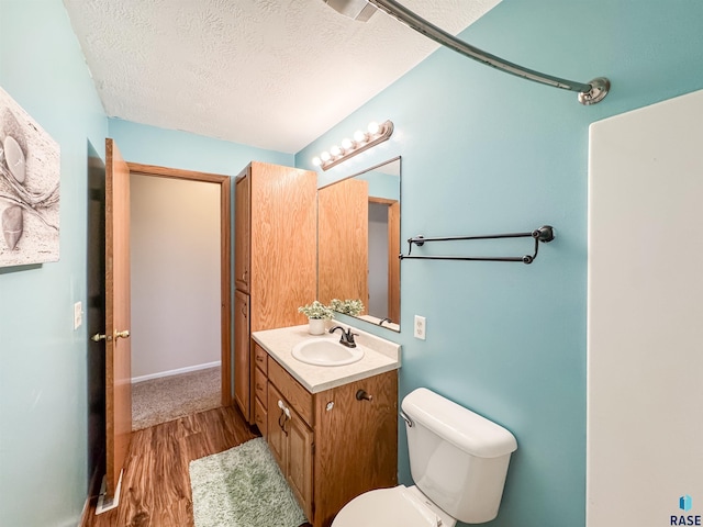 bathroom featuring vanity, toilet, wood-type flooring, and a textured ceiling