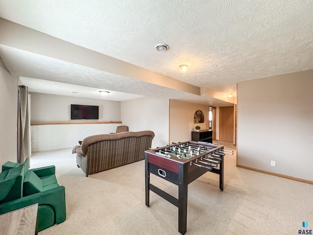 rec room featuring brick wall, light colored carpet, and a textured ceiling