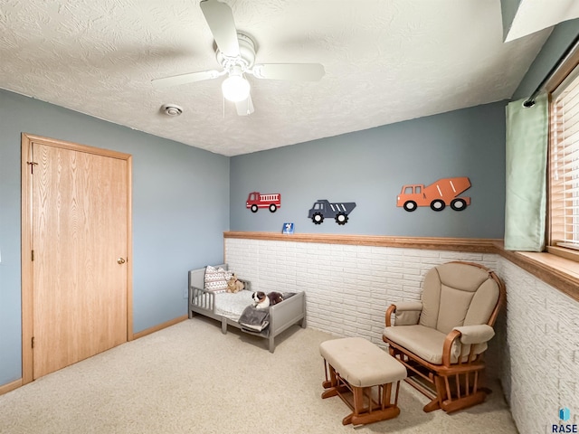 sitting room with carpet, a textured ceiling, ceiling fan, and a healthy amount of sunlight