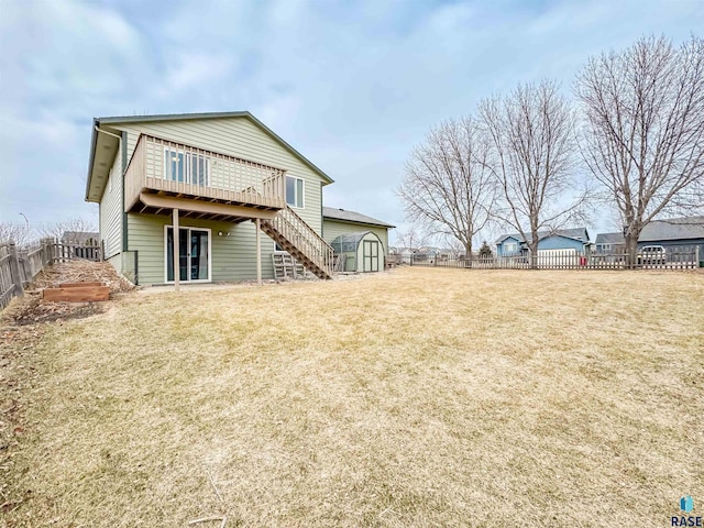 back of property featuring a storage shed, a yard, and a wooden deck