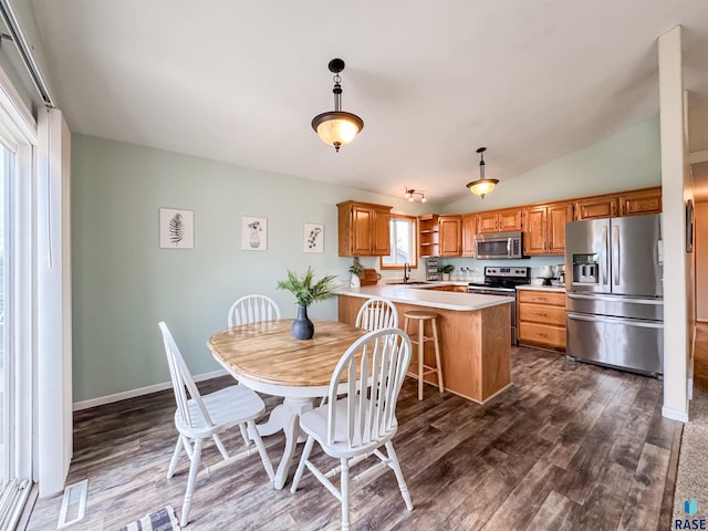 kitchen featuring kitchen peninsula, stainless steel appliances, vaulted ceiling, sink, and pendant lighting