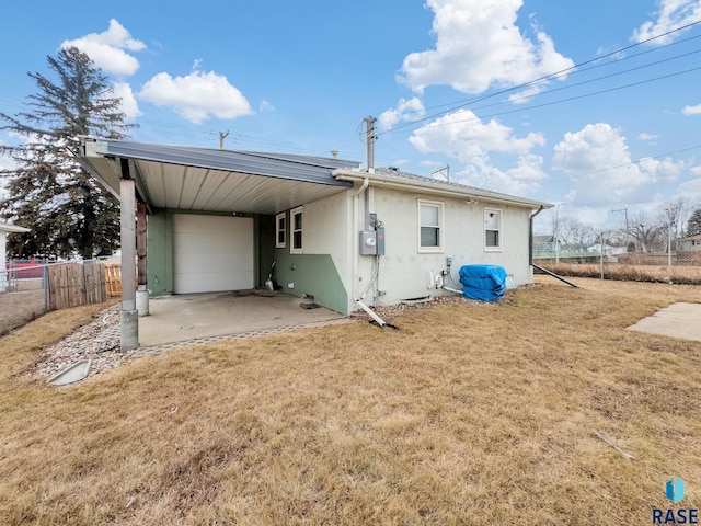 back of property with a garage, a carport, and a lawn