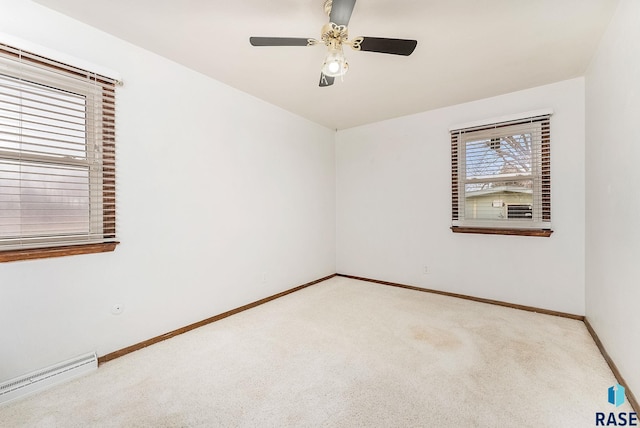 empty room with baseboard heating, light carpet, and ceiling fan