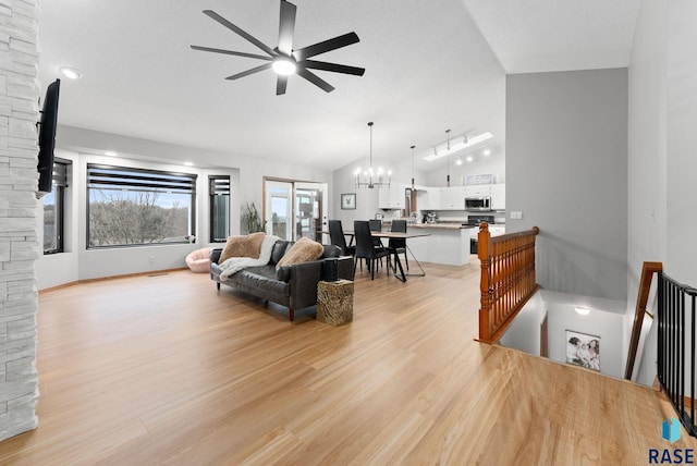 living room featuring light hardwood / wood-style flooring, ceiling fan with notable chandelier, and lofted ceiling