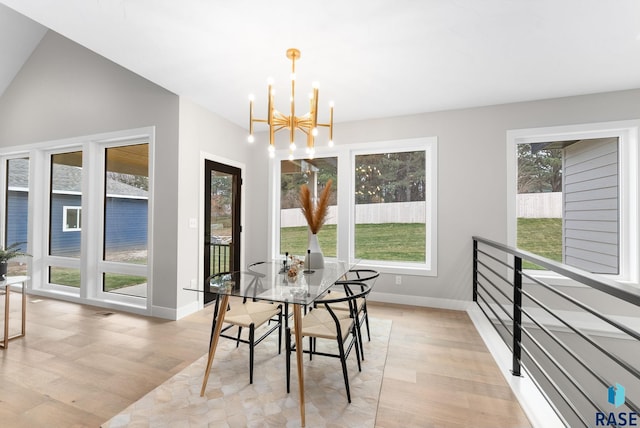 dining area with vaulted ceiling, light hardwood / wood-style floors, and an inviting chandelier