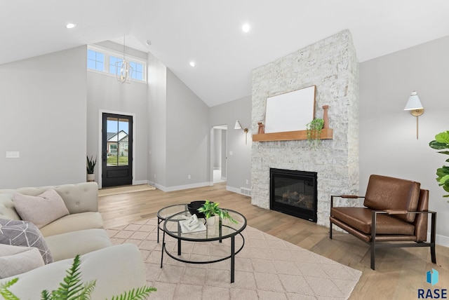 living room with light hardwood / wood-style floors, a fireplace, and high vaulted ceiling