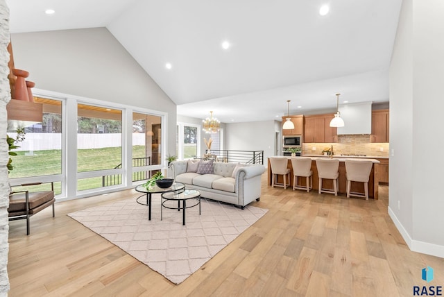 living room featuring light wood-type flooring, high vaulted ceiling, and an inviting chandelier