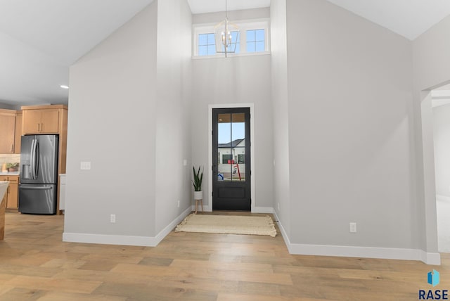 foyer with light hardwood / wood-style floors, a healthy amount of sunlight, a high ceiling, and a notable chandelier