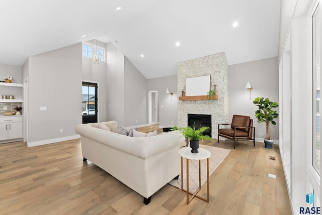 living room with a fireplace, high vaulted ceiling, and light wood-type flooring