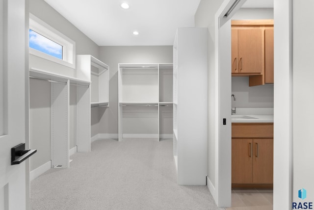 walk in closet with light colored carpet and sink