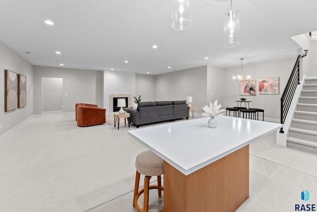 kitchen featuring a center island, hanging light fixtures, a kitchen bar, light carpet, and a fireplace