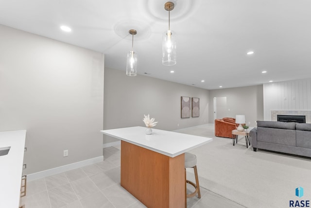 kitchen with light carpet, a kitchen bar, a kitchen island, and hanging light fixtures