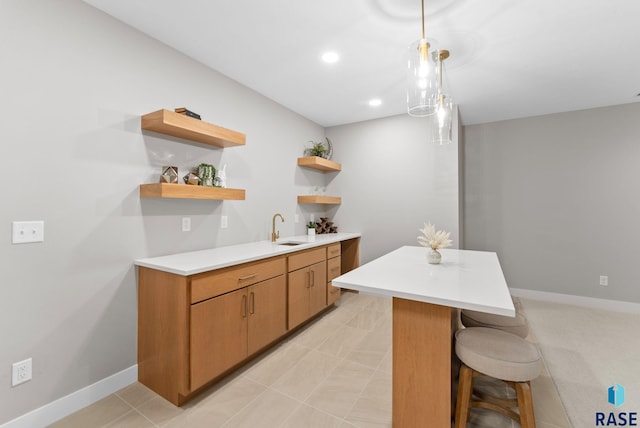 kitchen featuring kitchen peninsula, a kitchen breakfast bar, hanging light fixtures, and sink