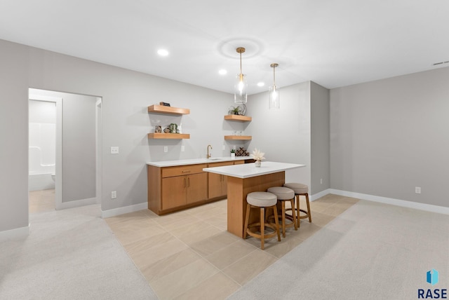 kitchen with sink, a kitchen bar, light tile patterned floors, and hanging light fixtures