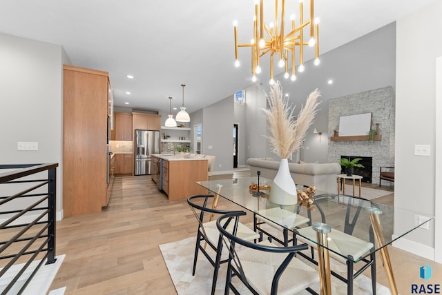 dining area with an inviting chandelier, light hardwood / wood-style flooring, a stone fireplace, and sink