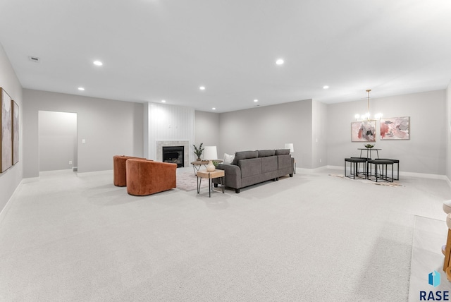 living room with light carpet, a large fireplace, and an inviting chandelier