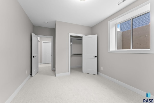 unfurnished bedroom featuring light carpet and a closet