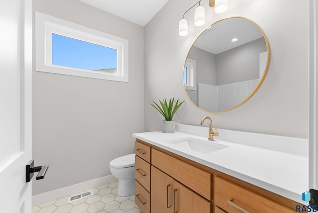 bathroom with walk in shower, vanity, and toilet