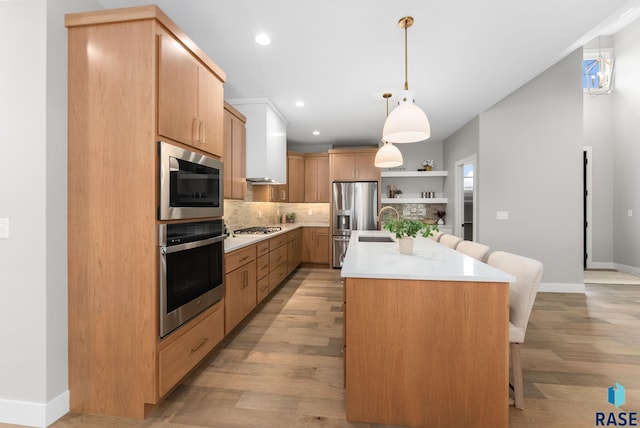 kitchen with stainless steel appliances, tasteful backsplash, a kitchen breakfast bar, pendant lighting, and a center island with sink