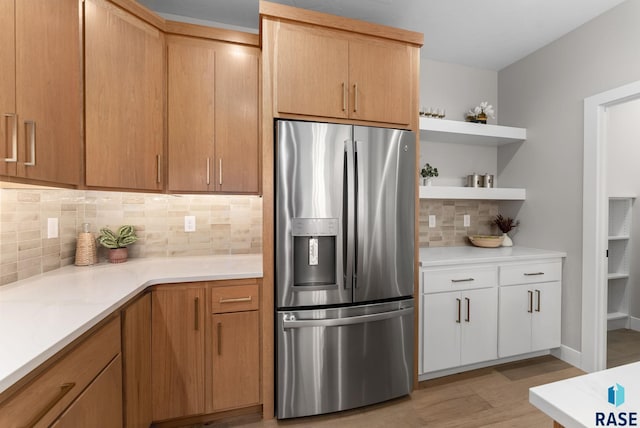 kitchen featuring white cabinetry, decorative backsplash, stainless steel fridge with ice dispenser, and light stone countertops