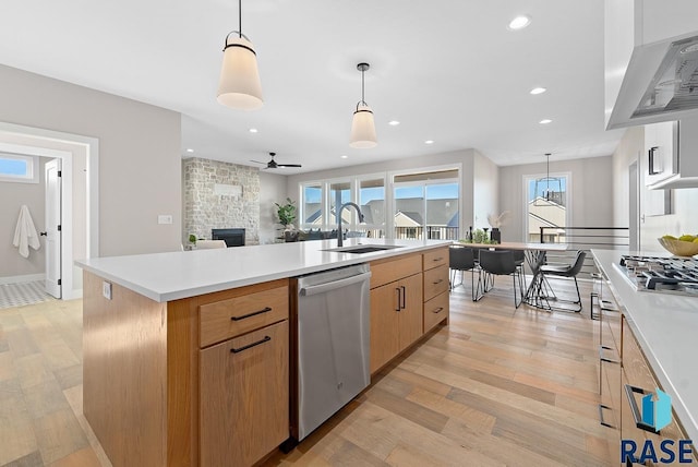 kitchen with pendant lighting, a stone fireplace, sink, a kitchen island, and stainless steel appliances