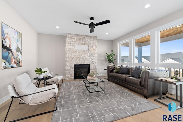 living room featuring a stone fireplace, ceiling fan, and hardwood / wood-style flooring