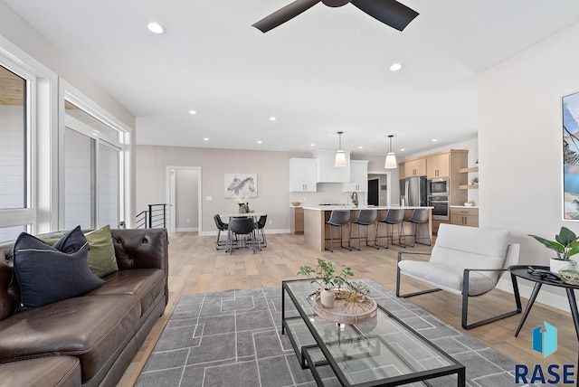 living room featuring ceiling fan, light hardwood / wood-style floors, and sink