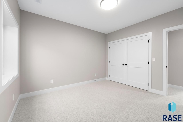 unfurnished bedroom featuring light carpet and a closet