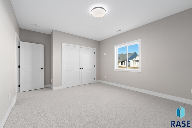 unfurnished bedroom featuring light carpet and a closet