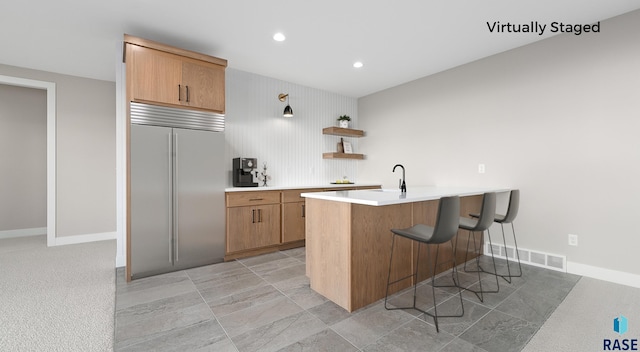 kitchen featuring sink, stainless steel built in refrigerator, kitchen peninsula, and a breakfast bar area