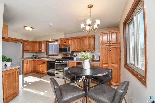 kitchen featuring a wealth of natural light, pendant lighting, stainless steel appliances, and an inviting chandelier