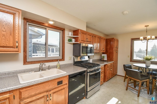 kitchen featuring appliances with stainless steel finishes, decorative light fixtures, a notable chandelier, and sink