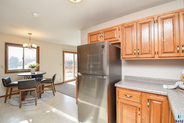 kitchen with pendant lighting, stainless steel refrigerator, and a chandelier