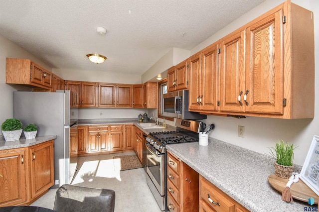 kitchen featuring a textured ceiling, stainless steel appliances, and sink