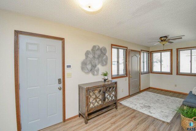 foyer featuring ceiling fan, light hardwood / wood-style floors, and a textured ceiling