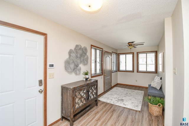 entryway with a textured ceiling, light hardwood / wood-style flooring, and ceiling fan