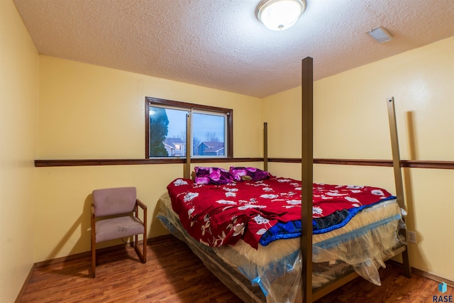 bedroom with a textured ceiling and hardwood / wood-style flooring