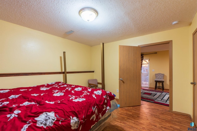 bedroom featuring wood-type flooring and a textured ceiling