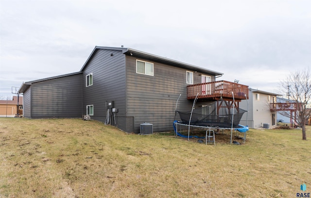 back of house featuring a wooden deck, a yard, cooling unit, and a trampoline