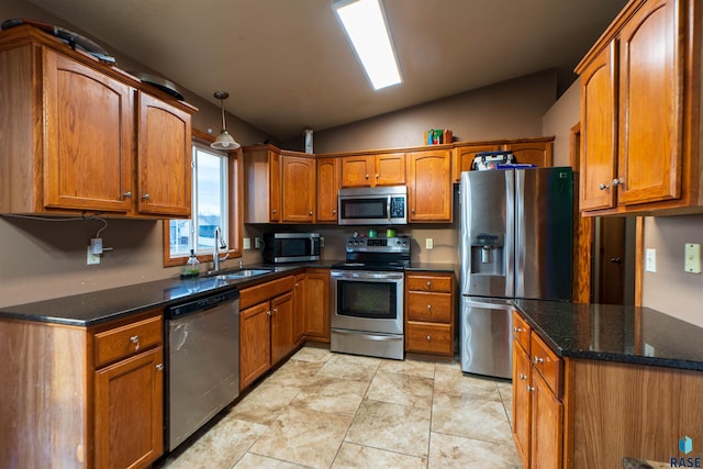 kitchen featuring lofted ceiling, hanging light fixtures, sink, dark stone countertops, and appliances with stainless steel finishes