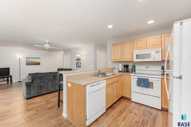 kitchen featuring ceiling fan, sink, kitchen peninsula, white appliances, and light brown cabinetry