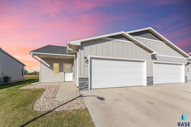 view of front of property with central AC unit, a garage, and a yard