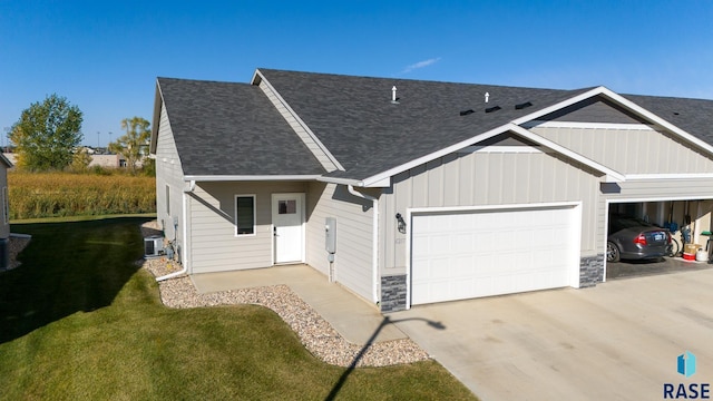 view of front facade featuring a garage, a front lawn, and central air condition unit