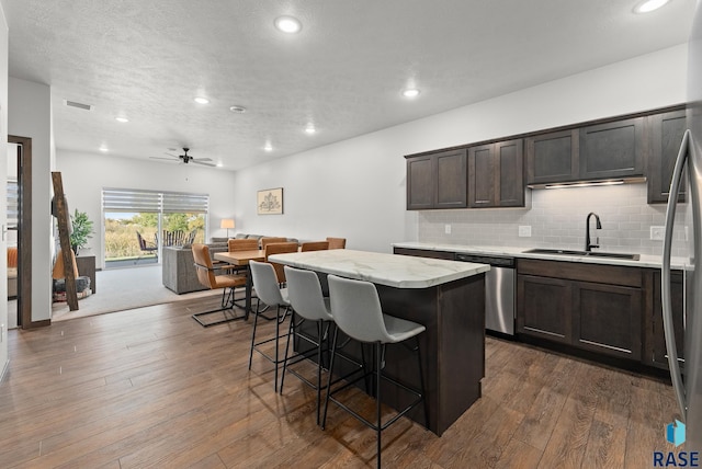 kitchen featuring appliances with stainless steel finishes, sink, dark hardwood / wood-style floors, a kitchen island, and a breakfast bar area