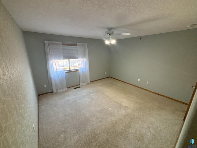 carpeted empty room with ceiling fan and a textured ceiling